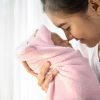 The newborn baby sleeping in the hands of the mother and their noses touching